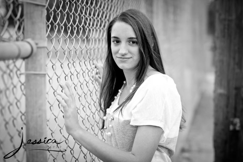 Senior Portrait of Michaela Hershberger with a chain link fence