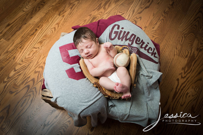 Newborn pic with baseball, glove, and father's jersey