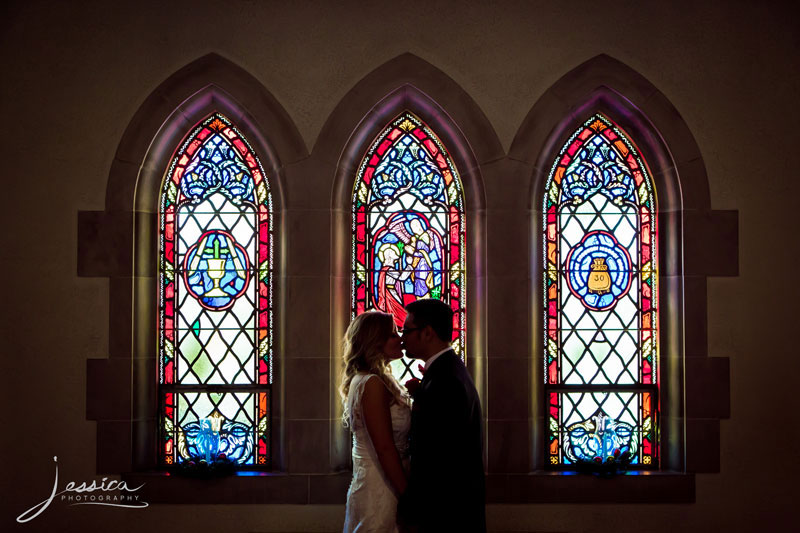 Portrait of groom and groom with stained-glass window