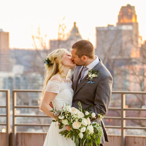 Bride and groom kissing at sunset with the Cincinnati skyline in the background