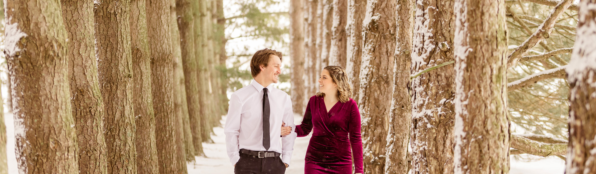Engaged couple walking through a pine forest